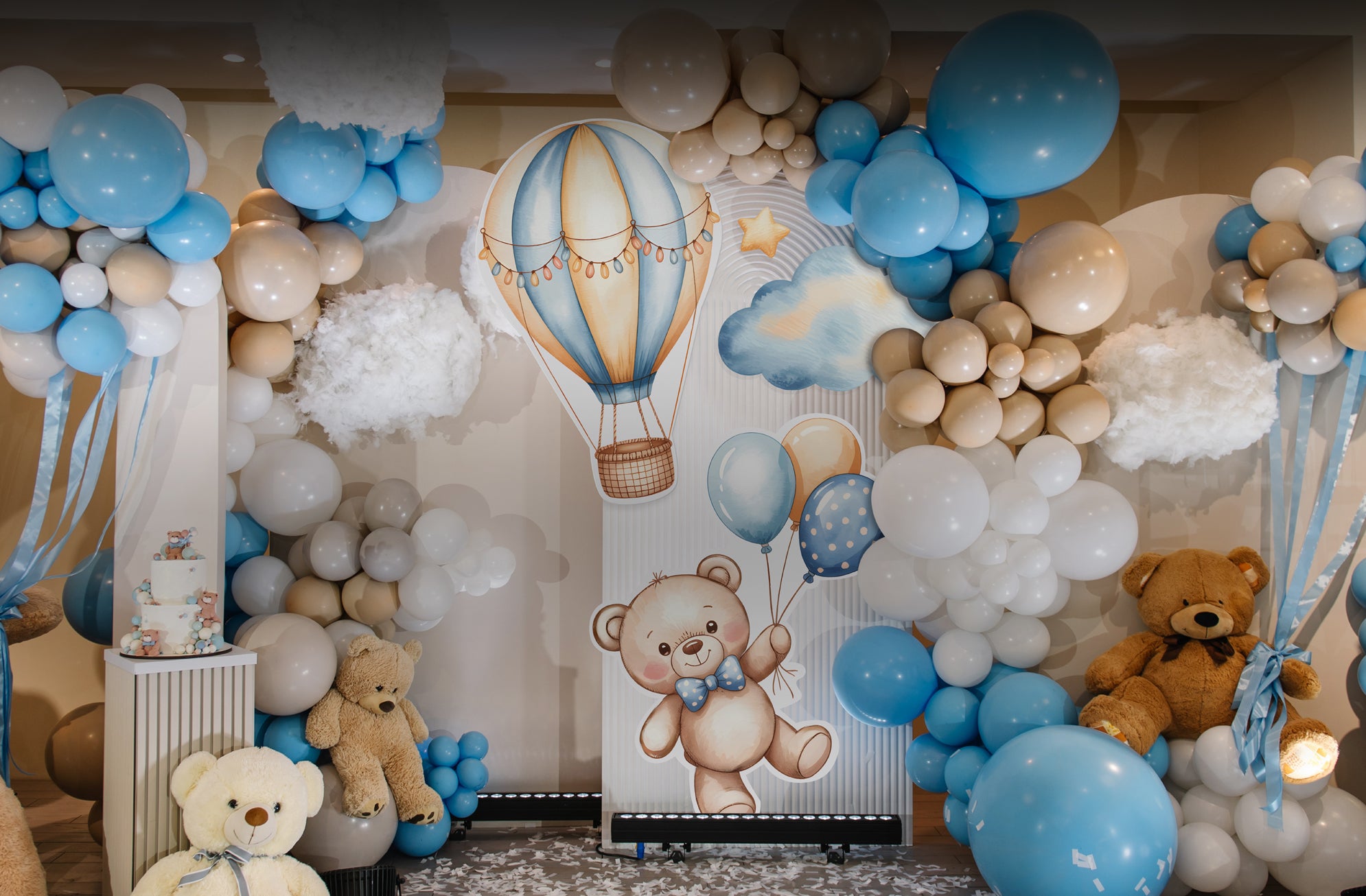 Decorative setup with balloons, teddy bears, and a backdrop featuring a teddy bear and hot air balloon.