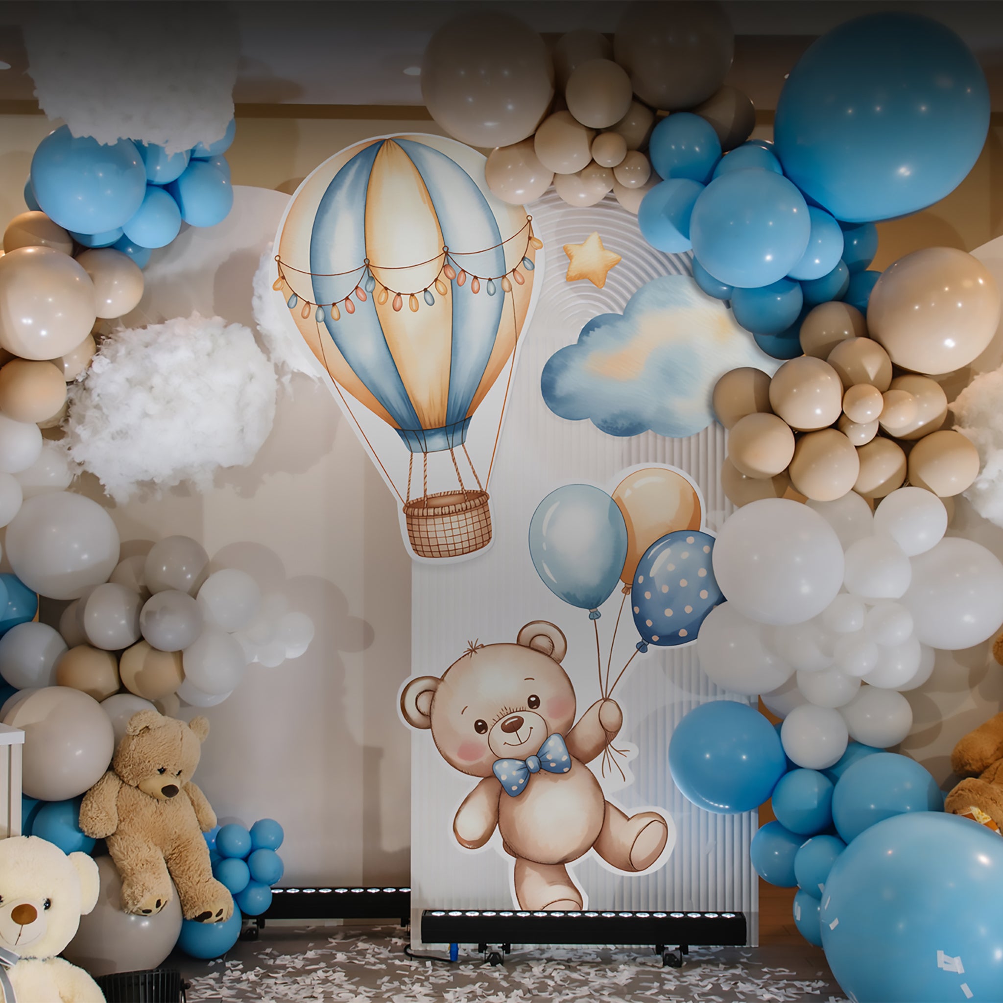 Decorative backdrop with teddy bear and balloons surrounded by balloons in a room setting.