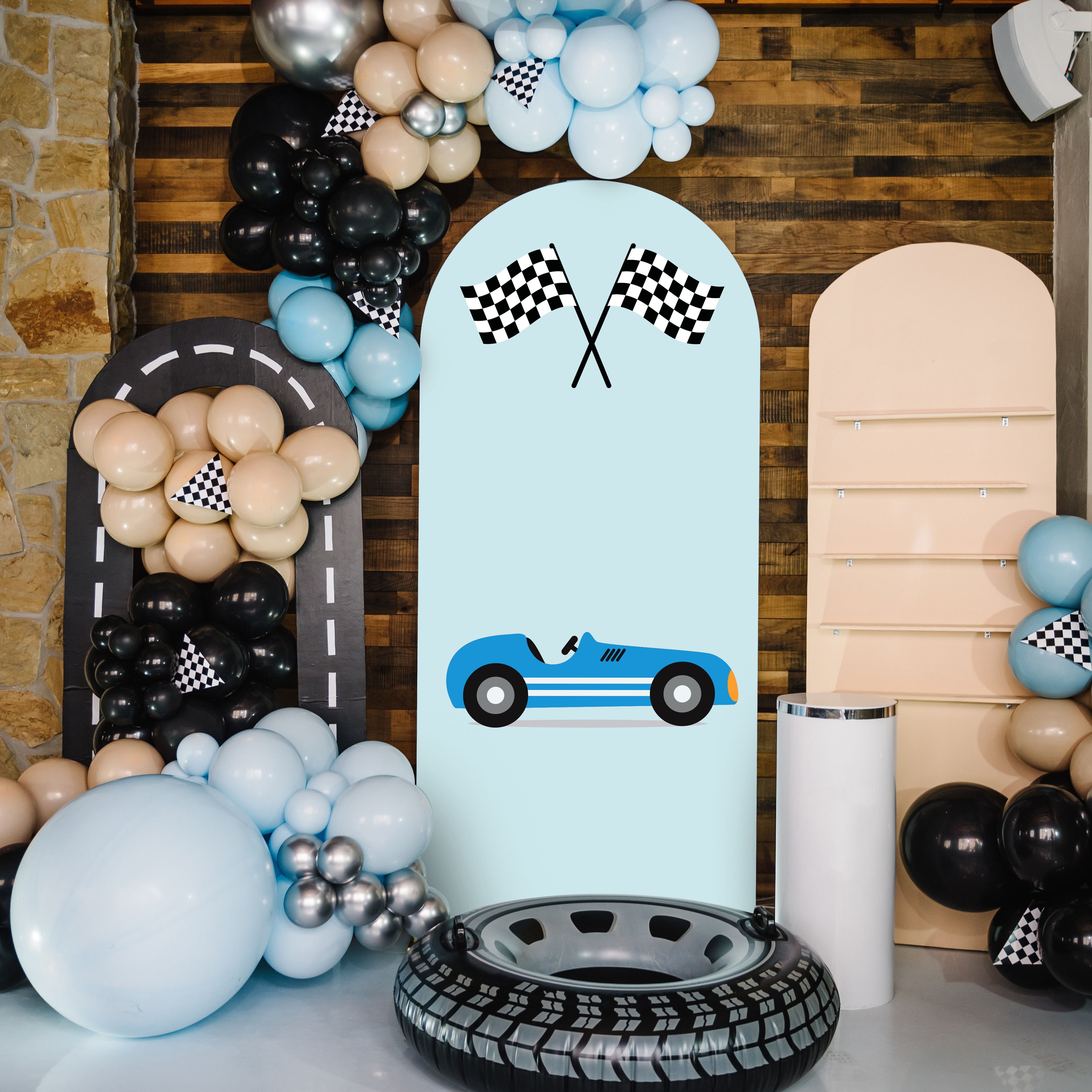 Decorative setup with balloons, a blue car graphic, and checkered flags on a light blue board.