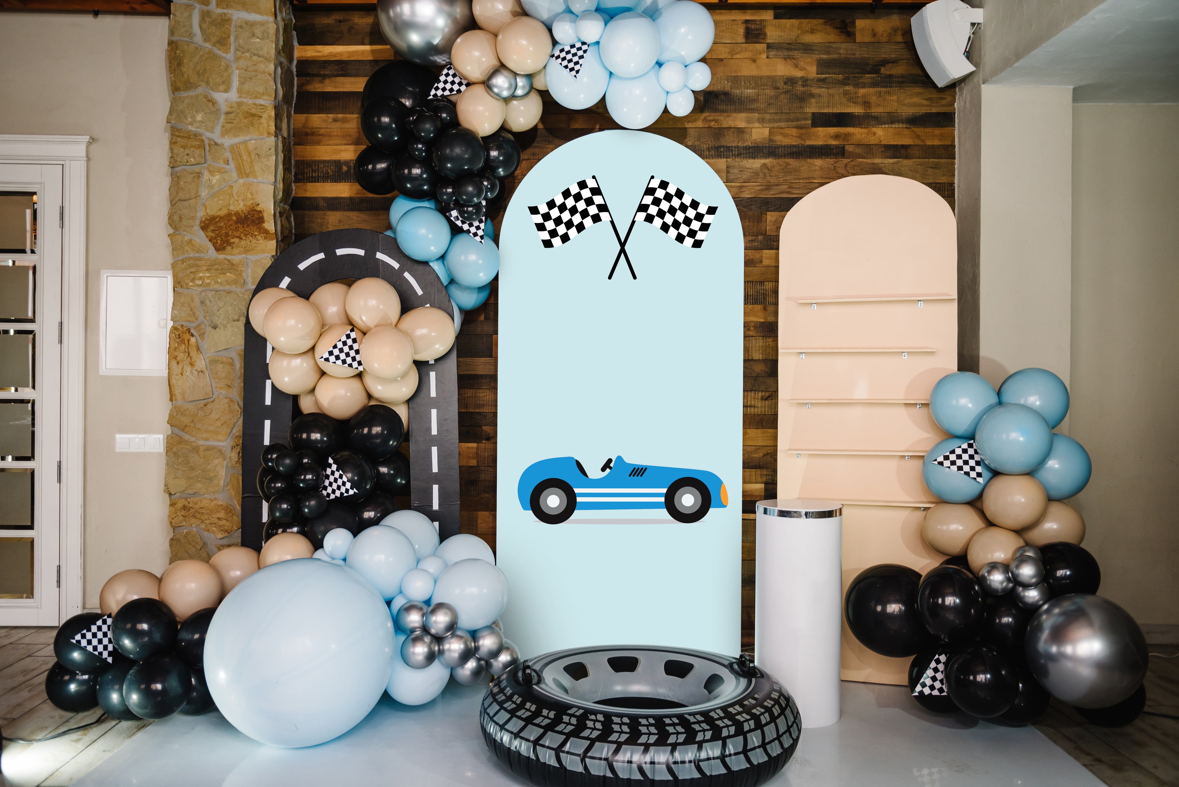 Decorative racing sailboard with balloons and a car-themed backdrop in a room.