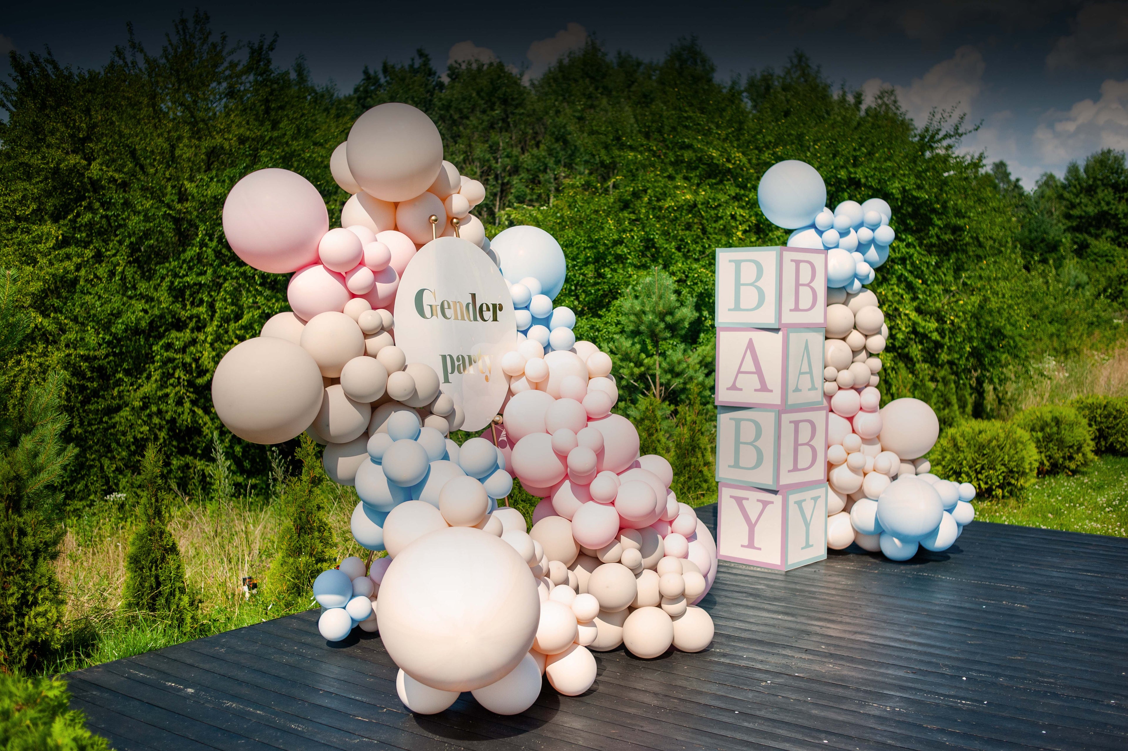 Balloon arch with 'Gender reveal' and 'Baby' blocks outdoors